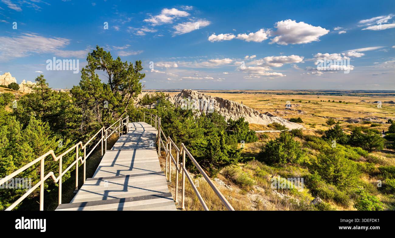 Cliff Shelf nature Trail se trouve dans le parc national des Badlands, Dakota du Sud, États-Unis. Des escaliers en bois traversent des genévriers verts et des forma rocheux Banque D'Images