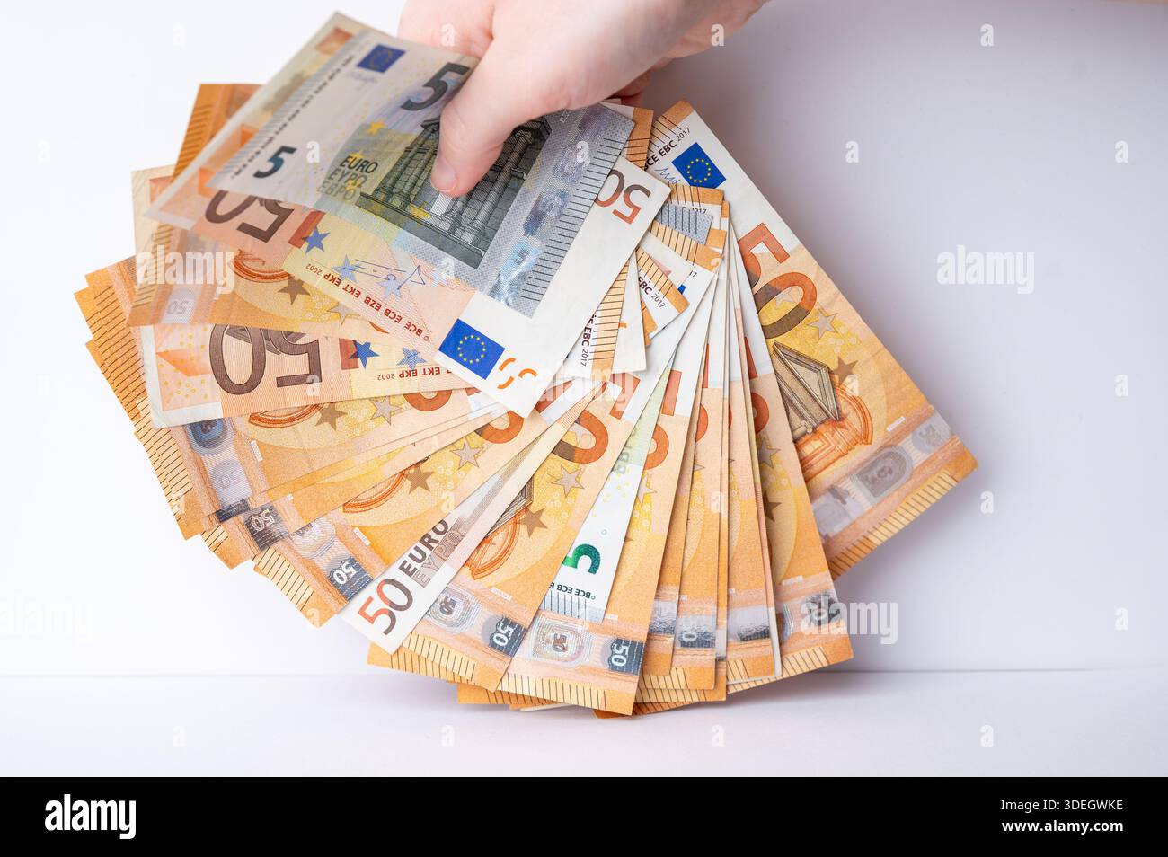 Une main saisit un éventail de billets en euros dans un cadre simple. Banque D'Images