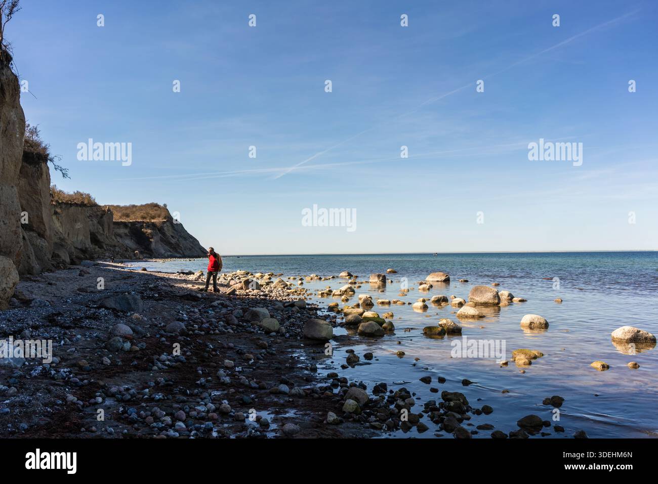 Un homme se balance sur des pierres le long de la côte de la mer Baltique près des falaises de Dornbusch sur l'île de Hiddensee, Mecklembourg-Poméranie occidentale, Allemagne Banque D'Images