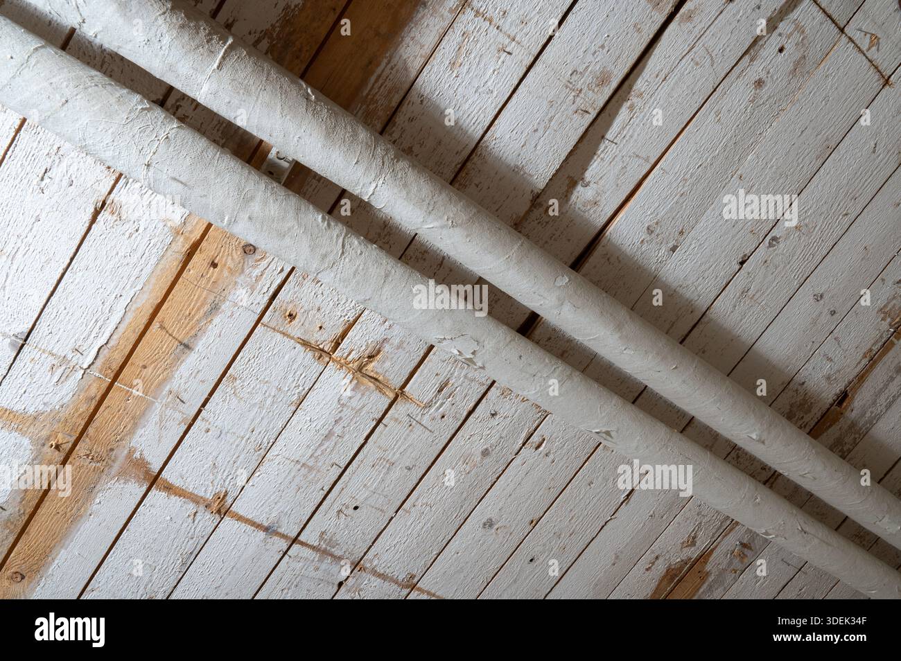 Gros plan d'un plafond en bois rustique avec des tuyaux exposés. Banque D'Images