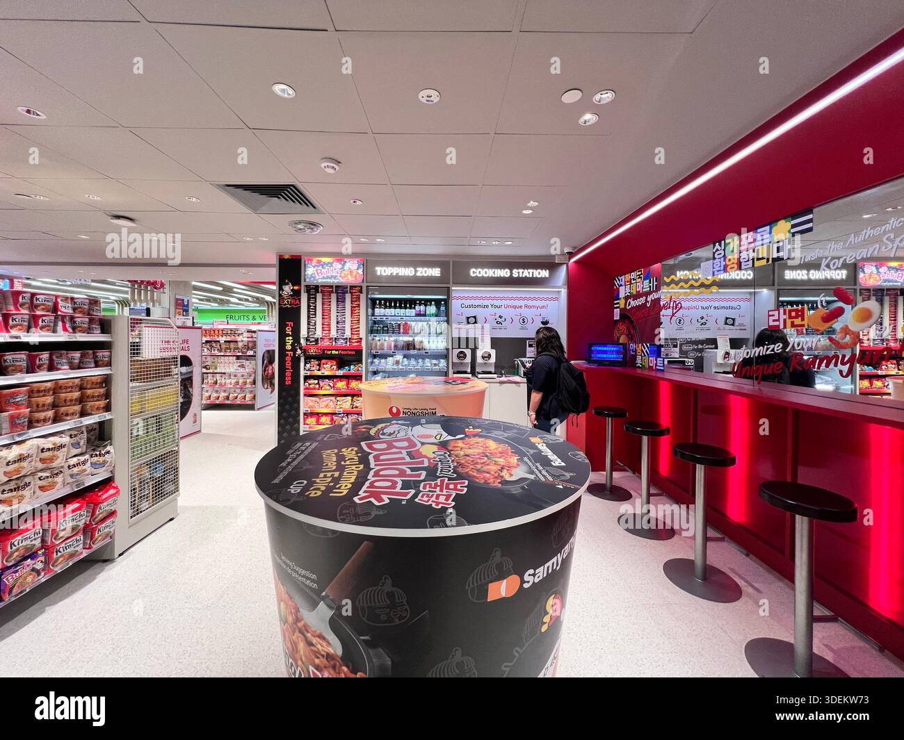 Lotte Mart Express ouvre ses portes à Singapour. Un client fait cuire des nouilles ramyun en arrière-plan. Il y a une table et des chaises à utiliser. Banque D'Images
