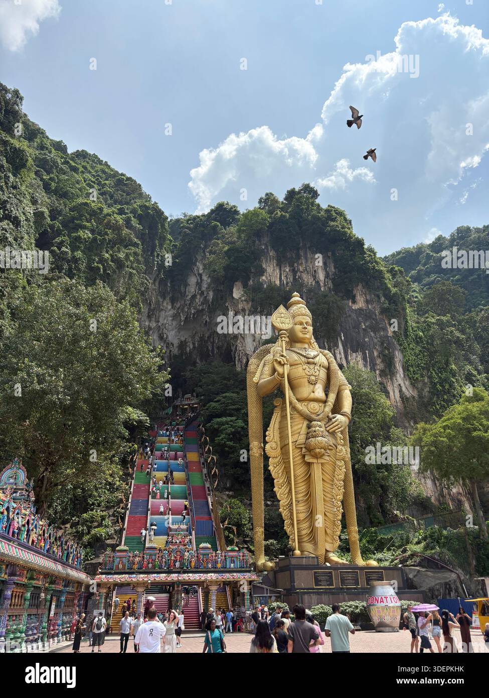 Imposante statue du Seigneur Murugan et escalier arc-en-ciel au complexe du temple des grottes de Batu, un lieu de pèlerinage animé. - Image de stock capturée avec un smartphone