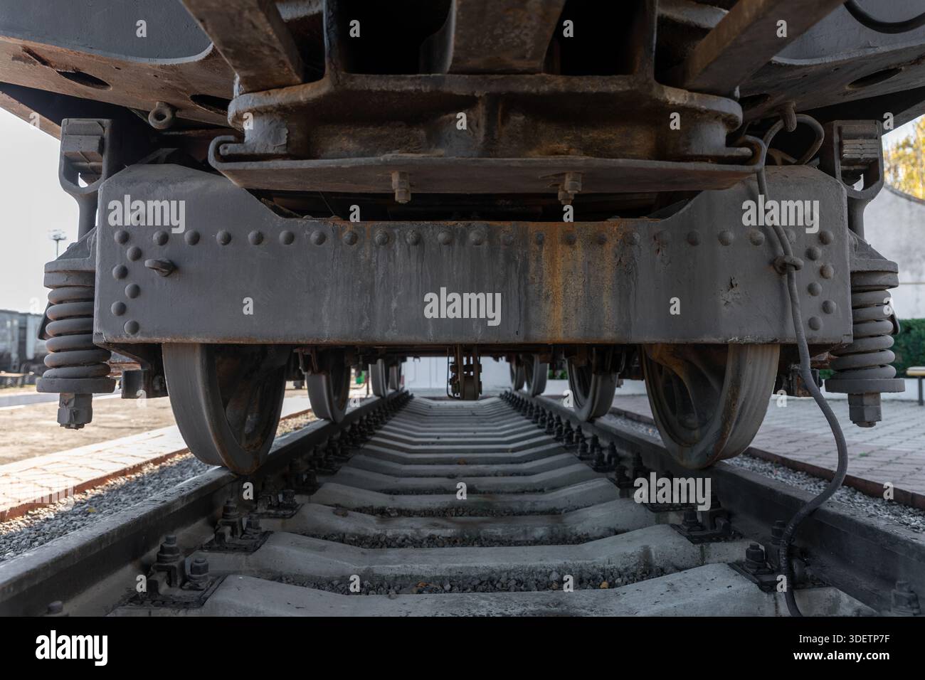Vue rapprochée des roues de train et du système de suspension du dessous, mettant en évidence les détails industriels et les voies ferrées pour les thèmes des transports. Banque D'Images