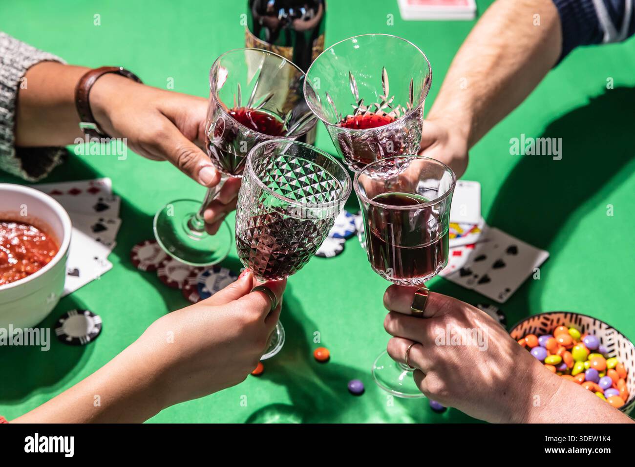 Amis grillant du vin tout en jouant au poker sur la table verte Banque D'Images