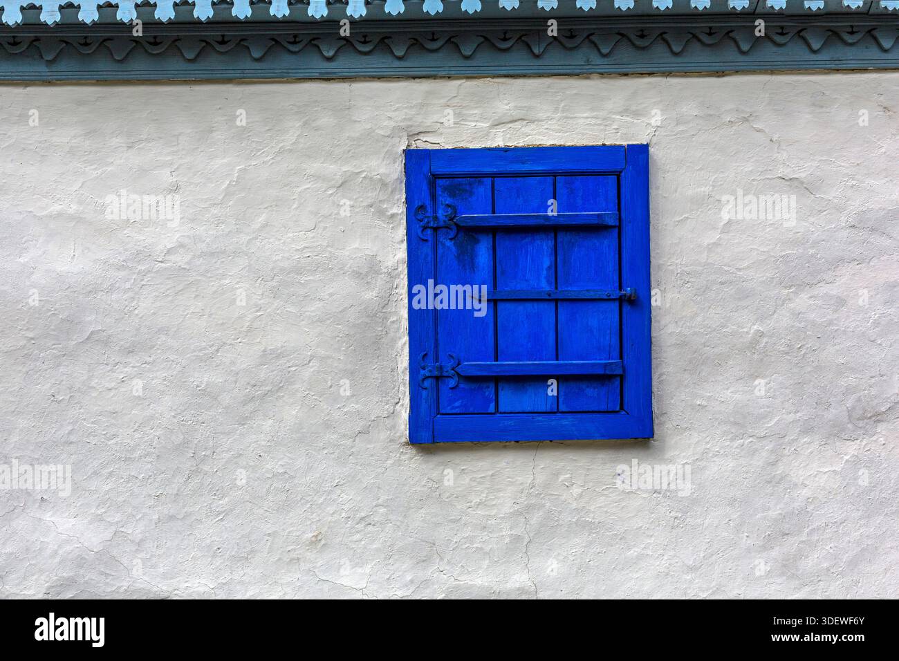 Volets bleus fermés sur un mur en stuc blanc avec garniture décorative en bois Banque D'Images