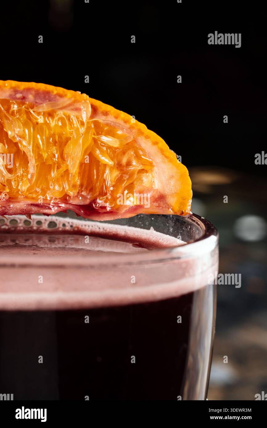 Une tranche fraîche d’orange repose sur le bord d’un verre, ajoutant un accent d’agrumes vif à la présentation de la boisson. Banque D'Images