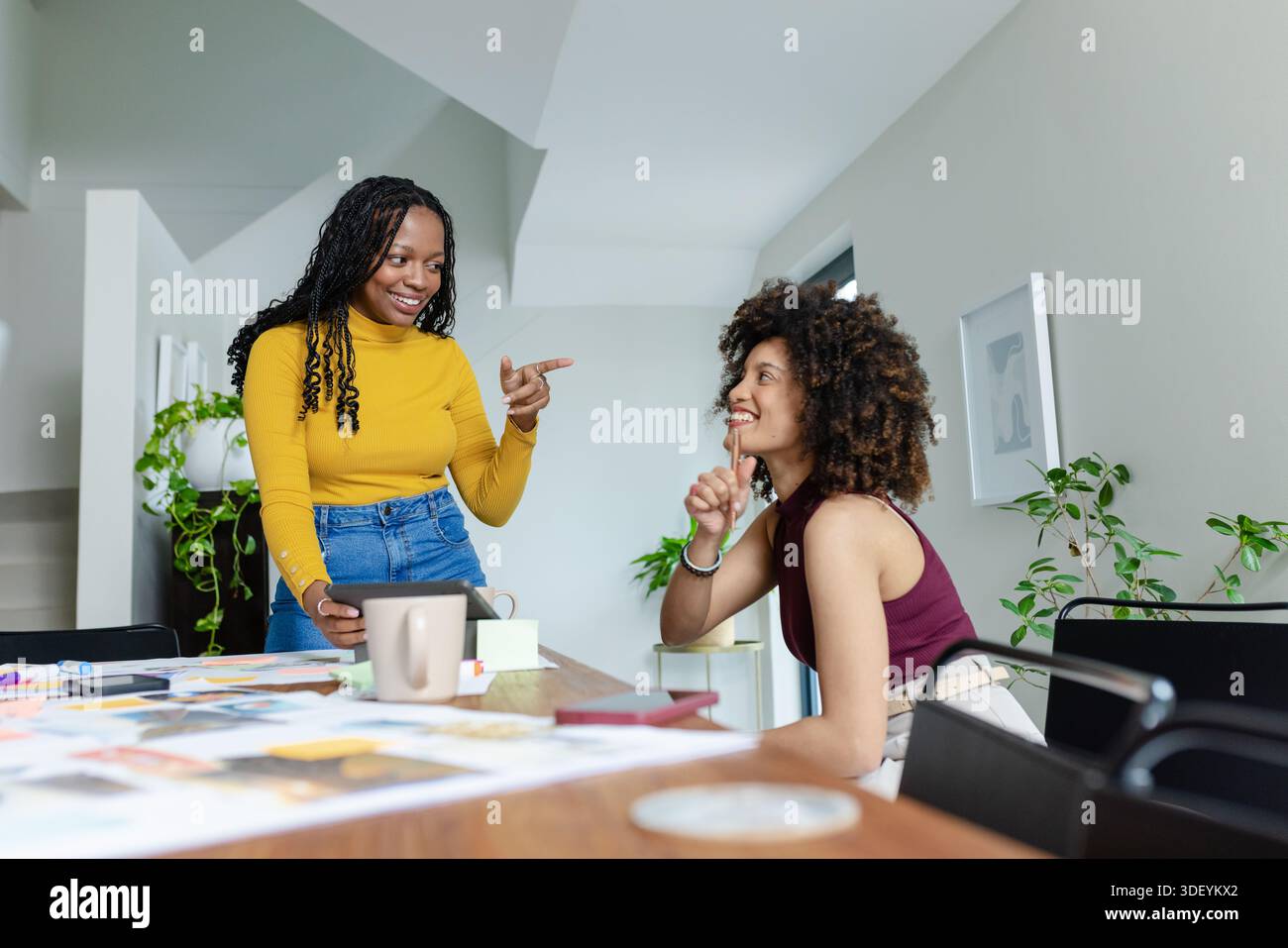 Diverses collègues féminines discutant des concepts à table en studio avec tablette, photos et échantillons Banque D'Images