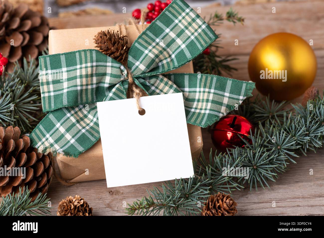 Cadeau de Noël avec étiquette cadeau carrée en papier sur une table blanche avec branches et décorations en sapin vue du dessus.Composition rustique en hiver avec Banque D'Images