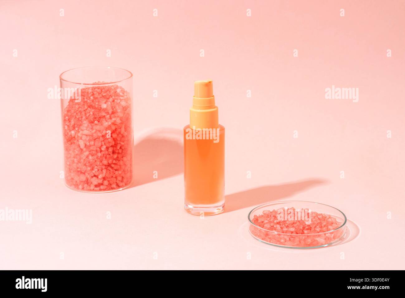 Bouteille cosmétique rose tendre avec du sel de cristal sur fond pastel avec des ombres. Produit de soin minimal, concept cosmétique naturel. Banque D'Images