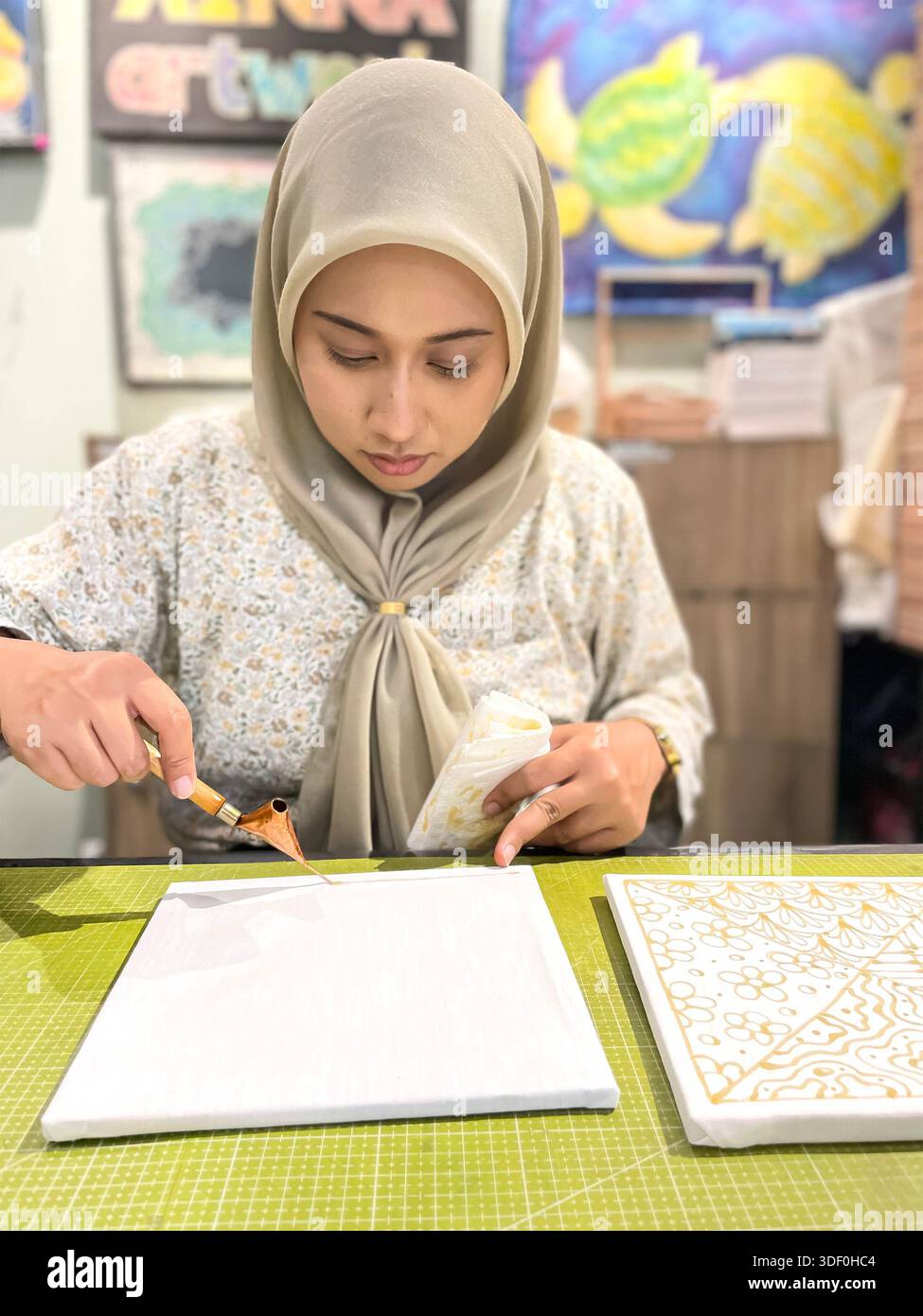 Jeune femme en hijab travaillant sur l'art géométrique islamique Batik avec un outil traditionnel dans un atelier de bureau de studio créatif Banque D'Images
