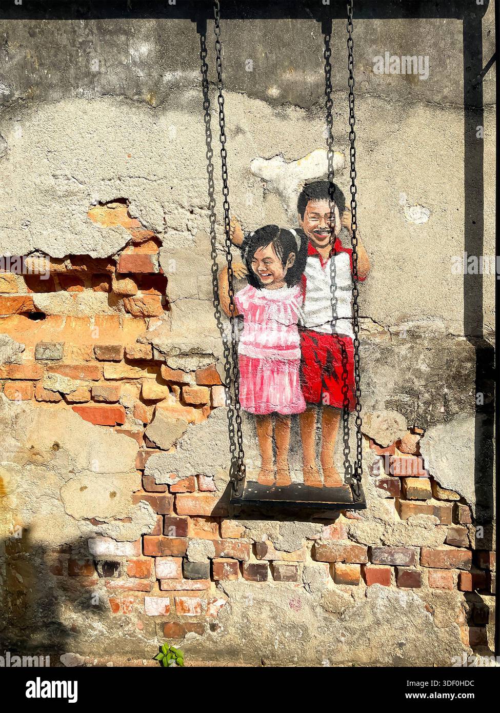 Peinture murale de Street art de deux enfants souriants sur une balançoire peinte sur un mur de briques et de plâtre altérés - Image de stock capturée avec un smartphone