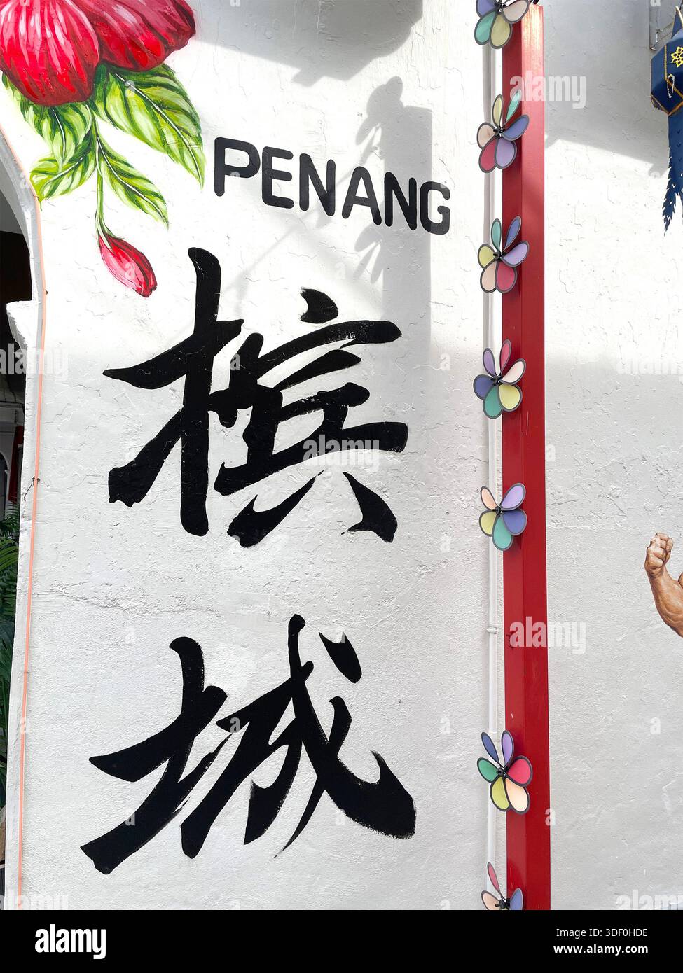 Peinture murale Street art à Penang avec calligraphie chinoise audacieuse, détails floraux décoratifs et éléments peints vibrants sur un mur blanc Banque D'Images