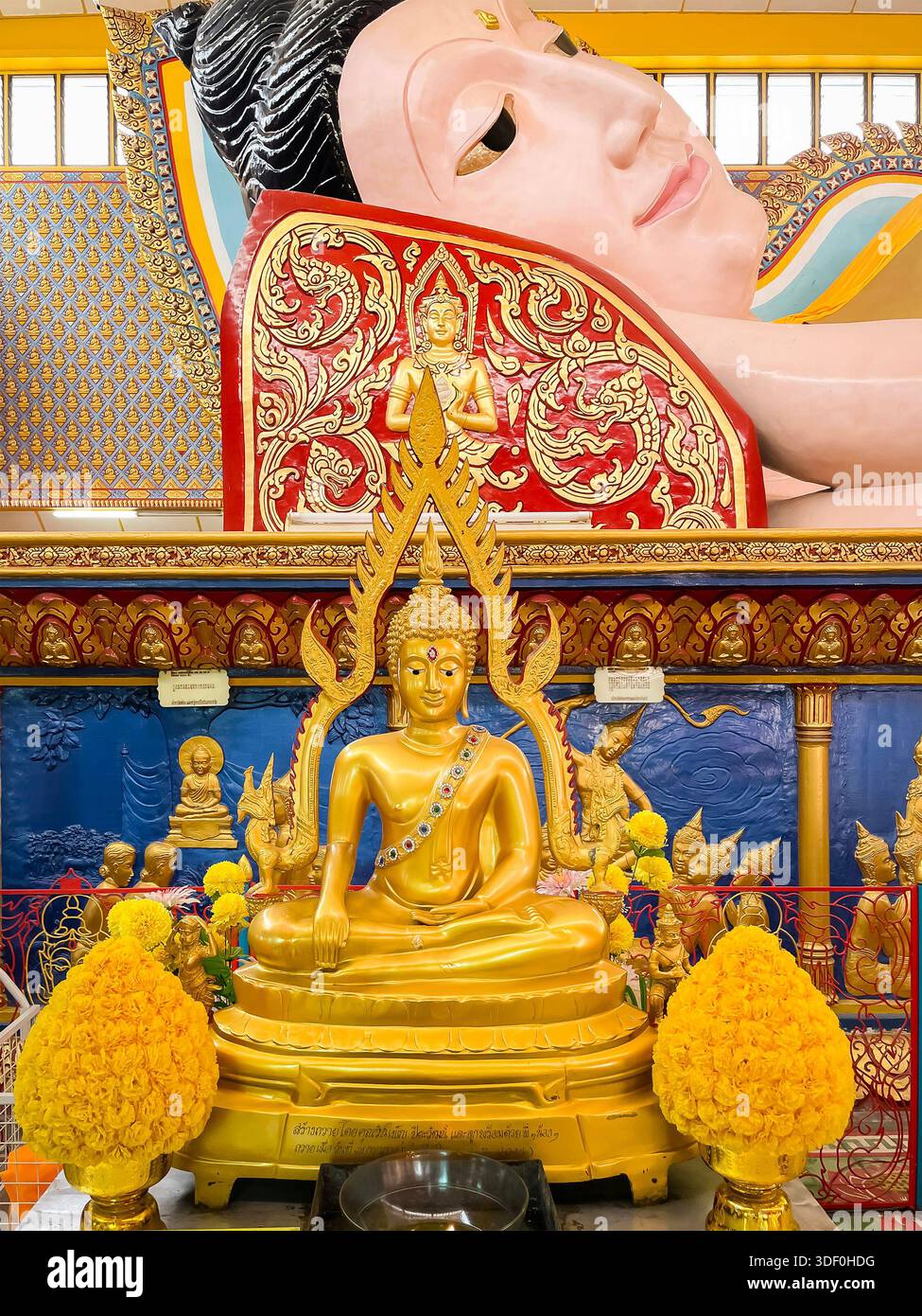 Statue de Bouddha doré avec des détails complexes devant le grand Bouddha couché à l'intérieur du temple Wat Chayamangkalaram décoré de manière vibrante à l'intérieur de penan Banque D'Images