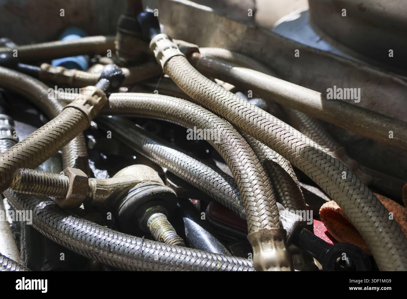 Pile encombrée de vieux tuyaux hydrauliques rouillés et de pièces de tuyaux automobiles sales et salissantes avec raccords industriels montrant une texture de réparation mécanique chaotique a Banque D'Images