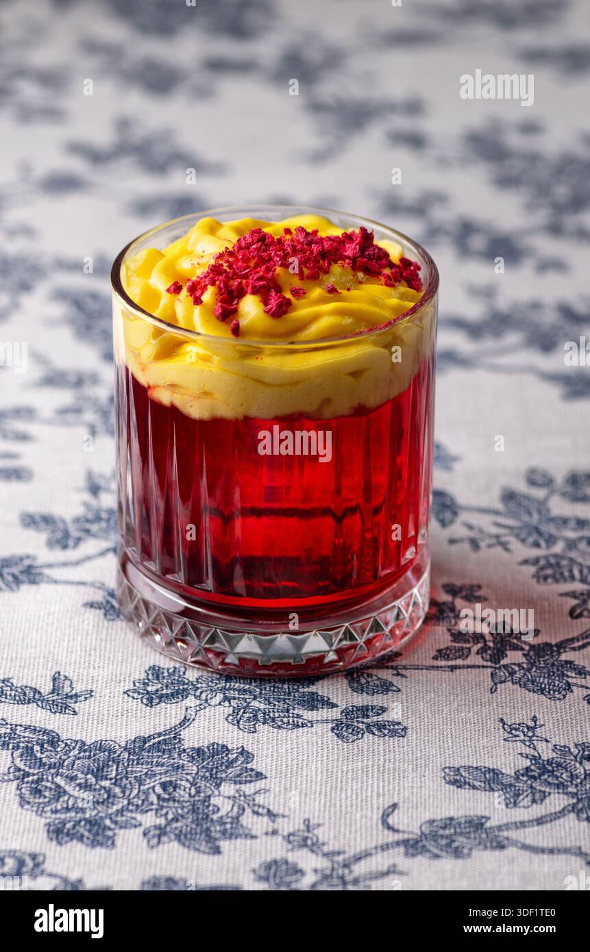Cocktail rouge avec mousse jaune et poudre de framboise. Banque D'Images