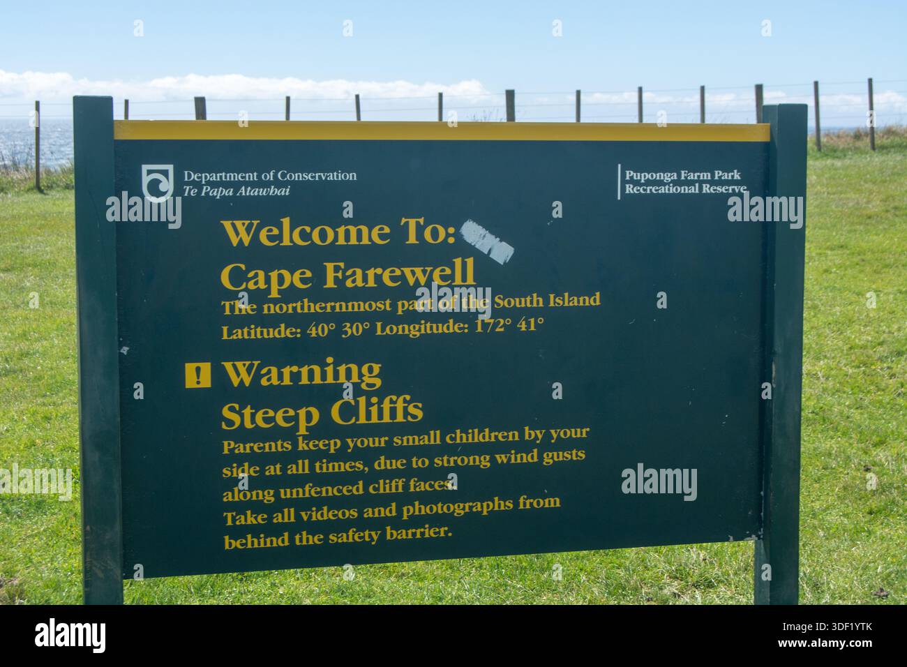Un panneau à Cape Farewell, Nouvelle-Zélande, indiquant l'emplacement et avertissant de falaises abruptes. L'enseigne présente un fond vert avec un texte jaune an Banque D'Images