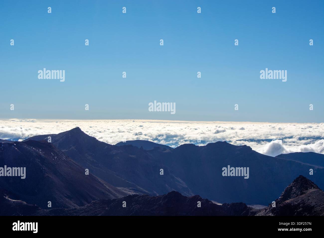 Une vue imprenable sur les sommets montagneux s'élevant au-dessus d'une mer de nuages sous un ciel bleu clair. Le terrain accidenté met en valeur la beauté de la nature, avec Sha Banque D'Images