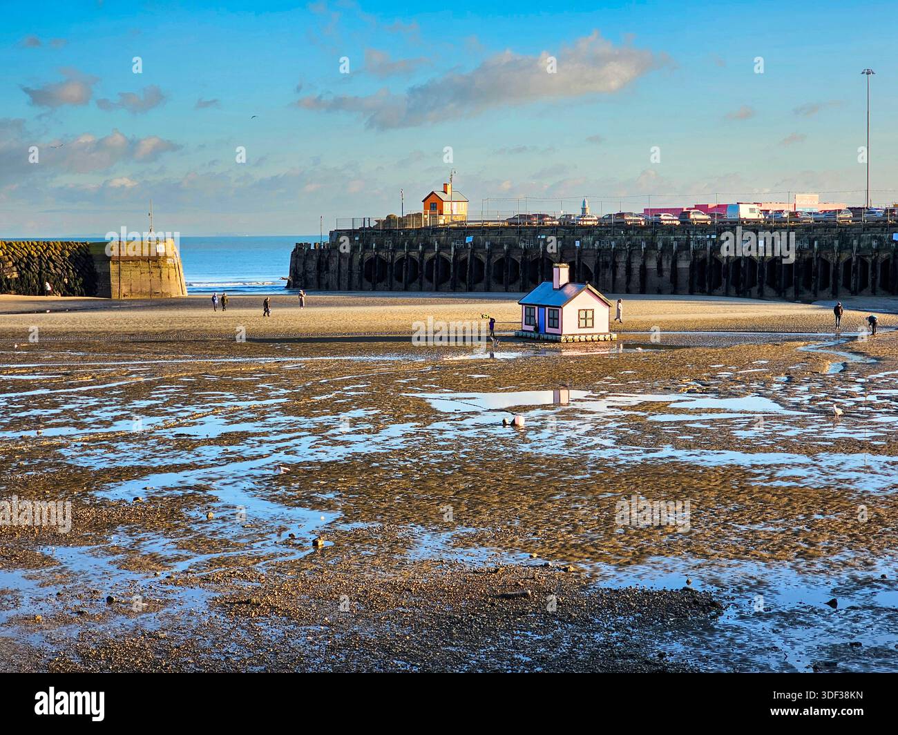 Port de Folkestone à marée basse. Les gens marchent sur le sable et la 'Pink House' est sur le sable. Banque D'Images