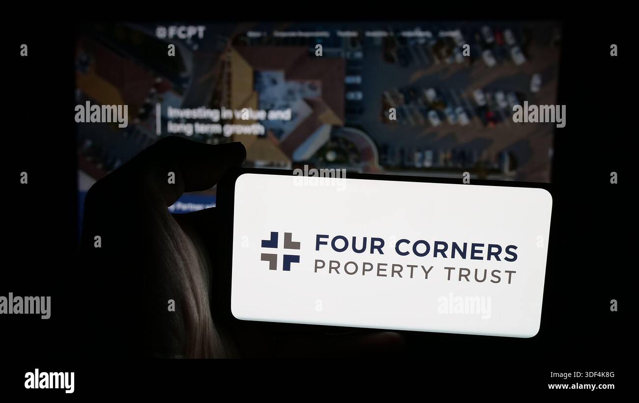 Stuttgart, Allemagne - 12-18-2025 : personne tenant un téléphone portable avec le logo de four Corners Property Trust Inc (FCPT) sur l'écran devant la page Web. Banque D'Images