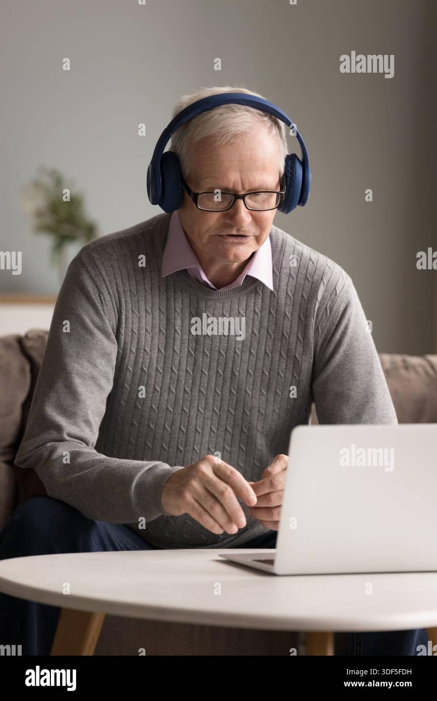 Homme mature portant des écouteurs parlant par téléconférence à l'aide d'un ordinateur portable Banque D'Images