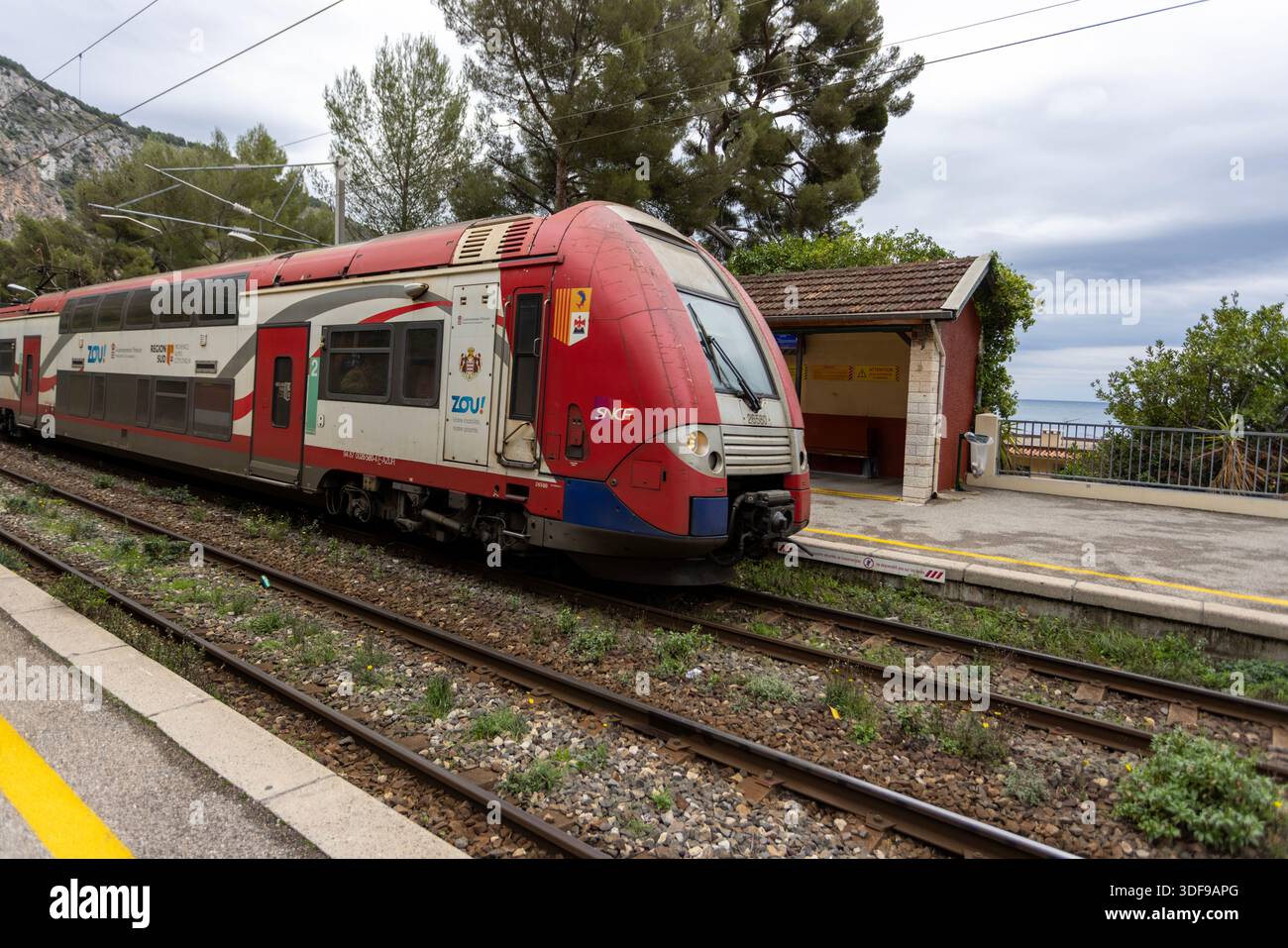 Eze, France -22 décembre 2025 : un train de transport express régional (TER) par SNCF arrive à la gare d'Eve en provenance de Monaco. Banque D'Images
