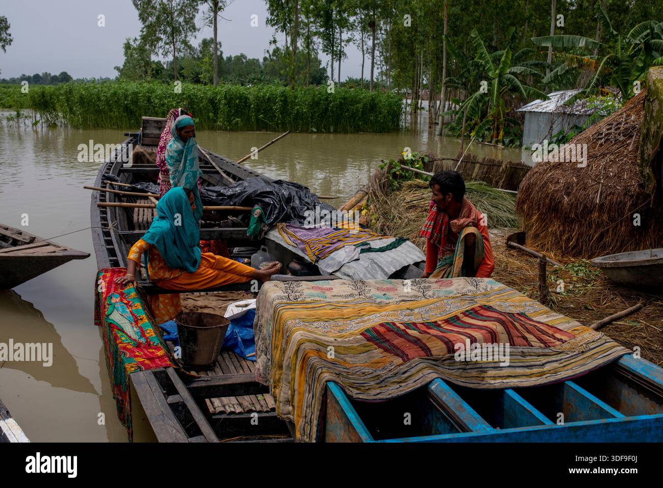 Les gens se réfugient sur des bateaux alors que les inondations submergent des maisons dans une zone de charpente le long de la rivière Jamuna à Sariakandi, Bogura, Bangladesh. Banque D'Images