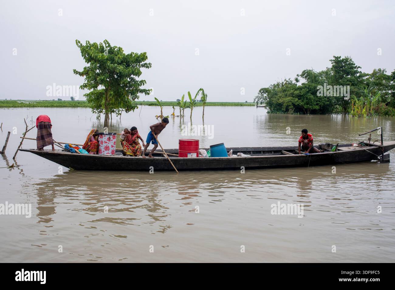 Les gens se réfugient sur des bateaux alors que les inondations submergent des maisons dans une zone de charpente le long de la rivière Jamuna à Sariakandi, Bogura, Bangladesh. Banque D'Images