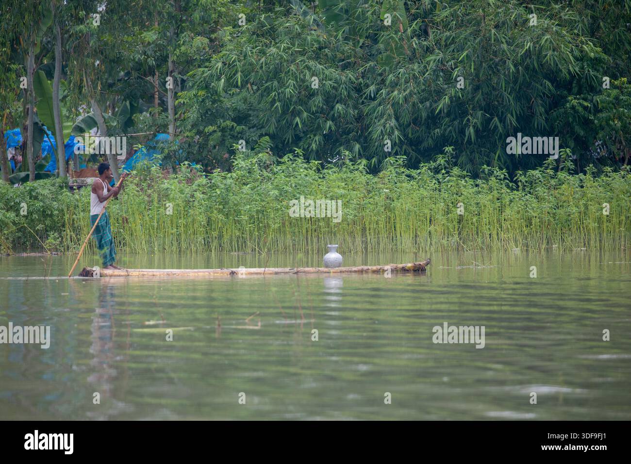 Un homme transporte de l’eau potable sur un radeau alors qu’il rentre chez lui en raison d’une crise d’eau potable dans la zone touchée par les inondations de Sariakandi, Bogura, Bangladesh Banque D'Images