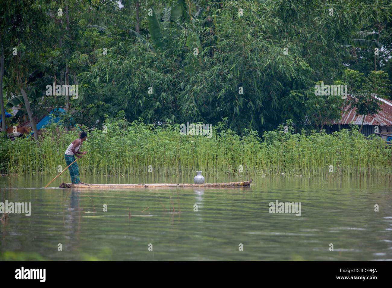 Un homme transporte de l’eau potable sur un radeau alors qu’il rentre chez lui en raison d’une crise d’eau potable dans la zone touchée par les inondations de Sariakandi, Bogura, Bangladesh Banque D'Images