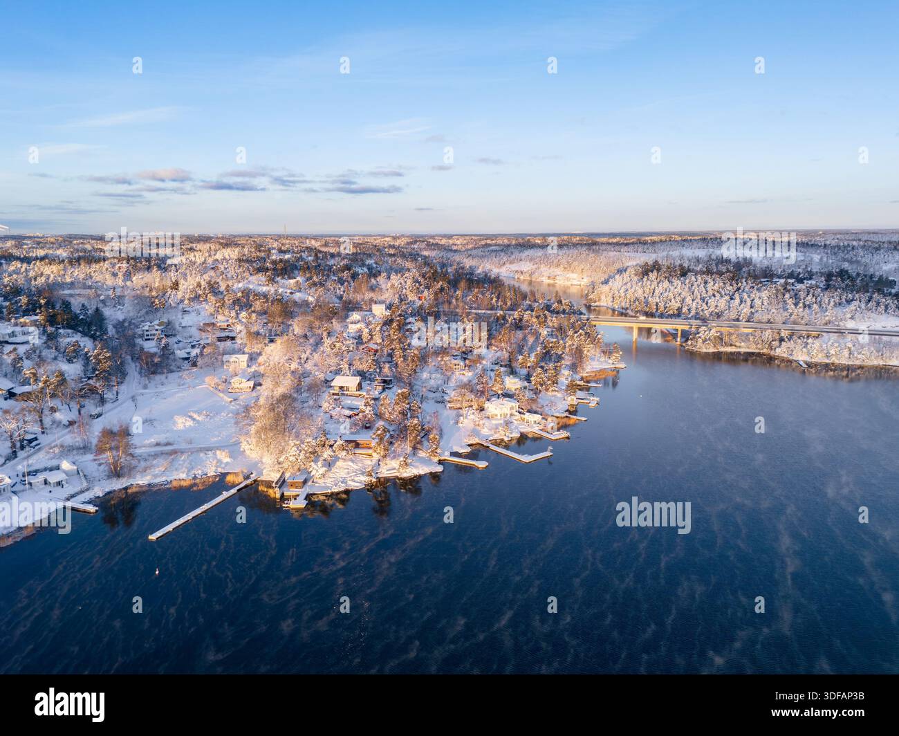 Beau lever de soleil sur l'archipel de Stockholm, Suède, après une tempête de neige, avec des maisons et des quais sur la colline Banque D'Images