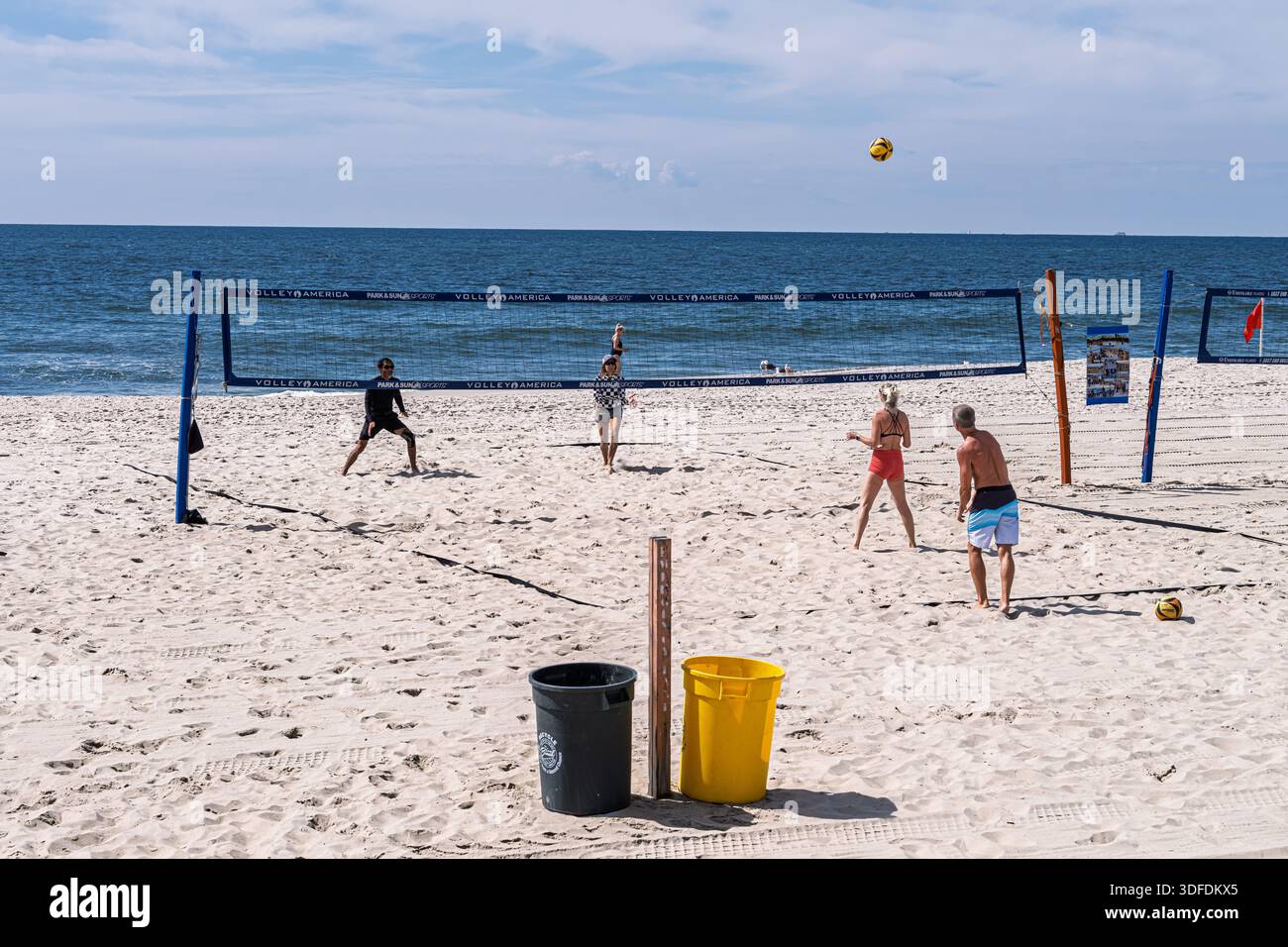 Les gens jouent au Beach volley sur les courts de sable le long du rivage de long Beach, long Island, New York, par une journée d'été claire. Banque D'Images