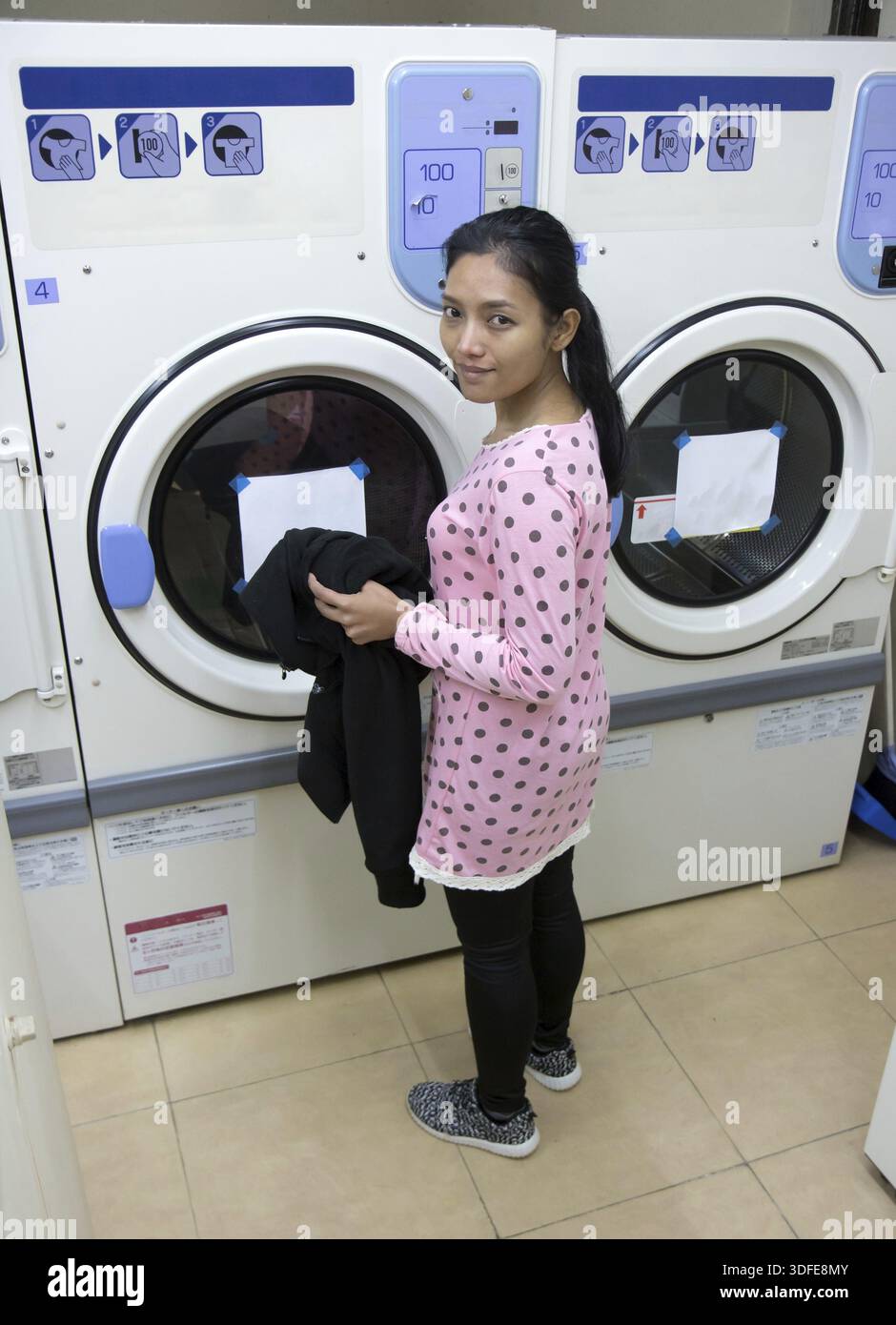 Jeune femme faisant la lessive dans la buanderie Banque D'Images