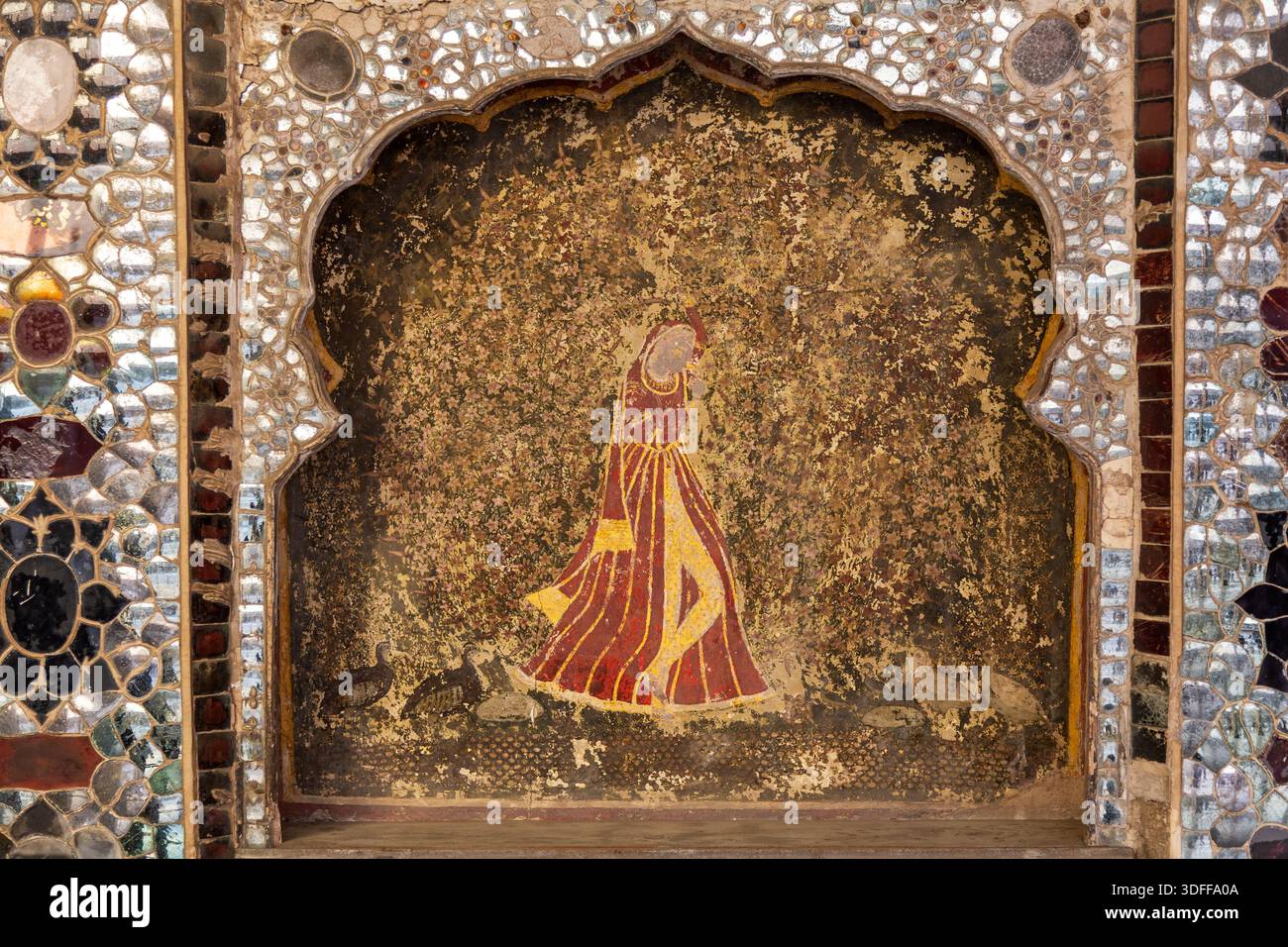 Vue d'une femme dans une robe rouge et or, peinte sur un mur et encadrée par des miroirs scintillants, reflétant la lumière et l'histoire dans le Fort de Lahore, Punjab, Paki Banque D'Images