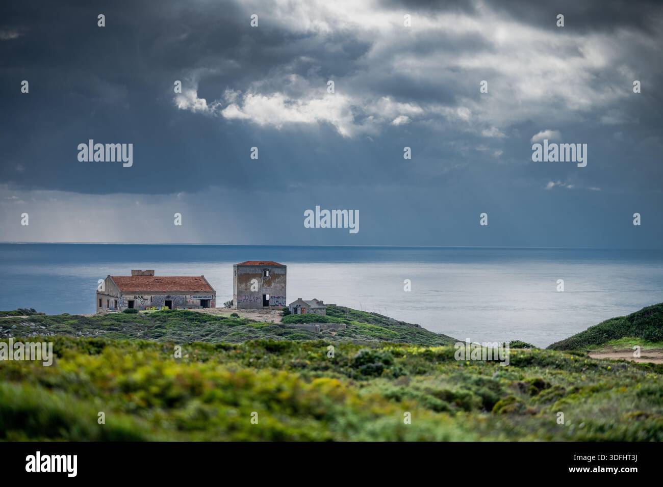 Sesimbra Portugal décembre 25 2025. Les bâtiments d'observation côtiers en ruine surplombent l'océan Atlantique sous les nuages hivernaux spectaculaires à Cabo Espichel. Banque D'Images