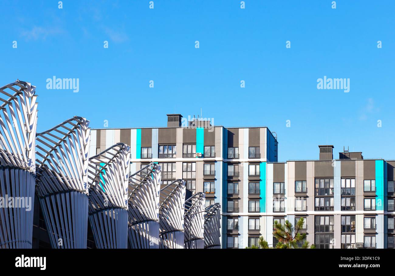 Immeubles résidentiels modernes avec des accents verticaux gris, blancs et turquoise, vus derrière des structures architecturales métalliques uniques sous un Banque D'Images