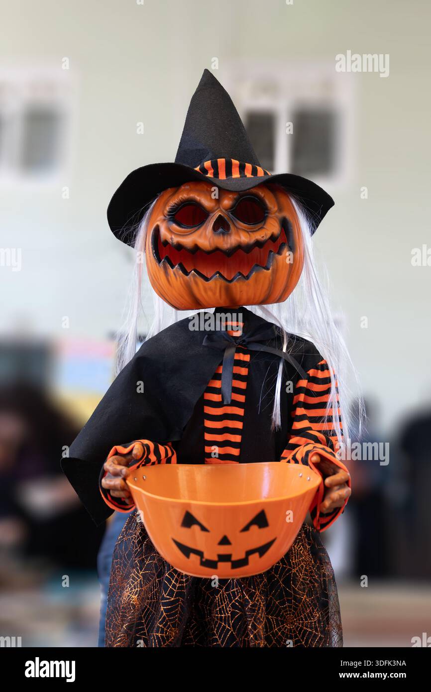 Figurine de sorcière d'Halloween effrayante avec une tête de citrouille tenant un seau de bonbons pour le trick-or-Treatment Banque D'Images