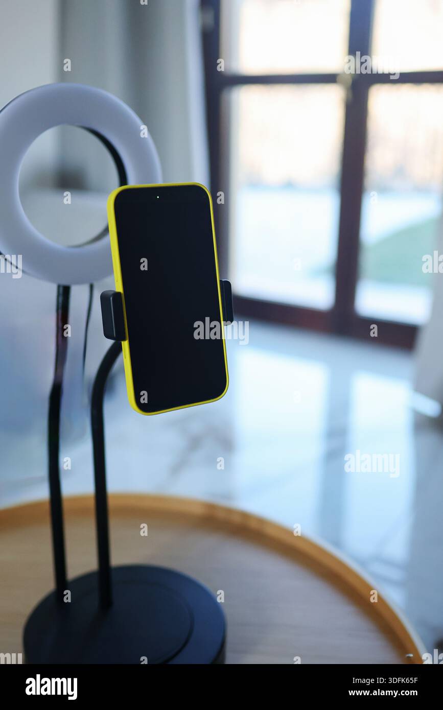 Téléphone portable sur trépied avec lumière annulaire dans un intérieur lumineux. Configuration des blogs pour les appels vidéo, l'éducation en ligne, le travail d'influenceur et le home studio. Banque D'Images