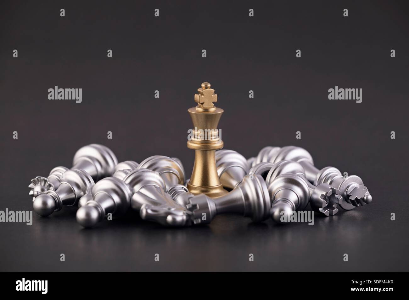 Roi d'or victorieux avec groupe de pièces d'échecs argentées couchées Banque D'Images