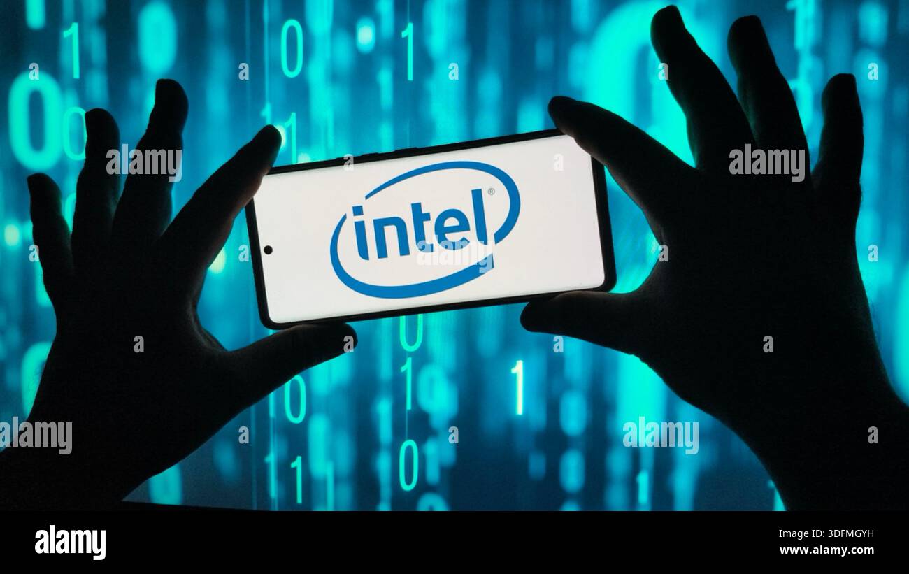 Silhouette mains tenant un smartphone affichant le logo Intel sur fond de données numériques, représentant la technologie et l'innovation informatique - Image de stock capturée avec un smartphone