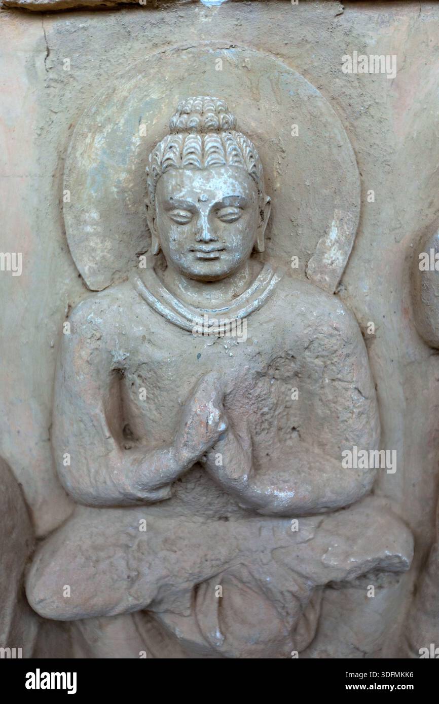 Vue d'une ancienne sculpture en pierre de Bouddha dans une pose méditative, mains doucement serrées, rayonnant de sérénité contre un simple halo, Taxila, Khyber Pakhtu Banque D'Images