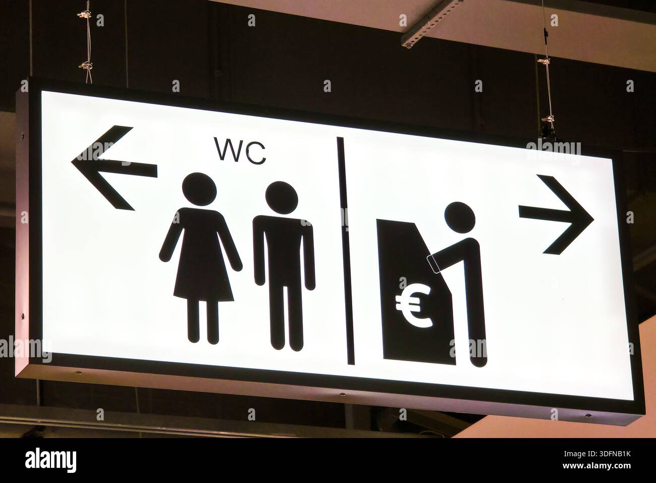 Panneau lumineux des toilettes publiques avec pictogrammes masculins et féminins, flèches directionnelles et symbole de guichet automatique dans un espace public intérieur moderne Banque D'Images