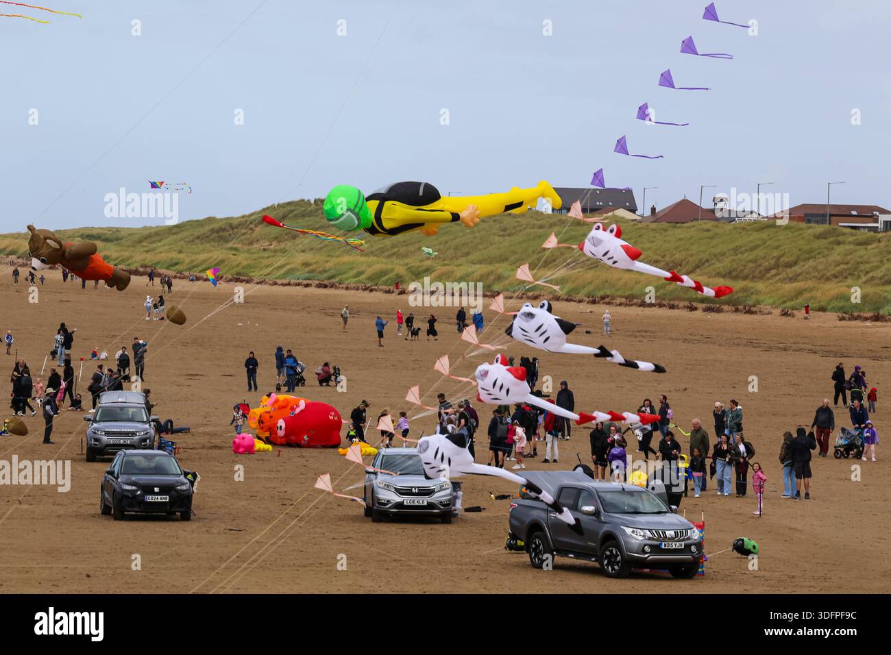 Cerfs-volants gonflables géants volant au-dessus de la plage lors d'un festival de cerf-volant à Lytham St Annes, avec des foules profitant de l'événement balnéaire. Banque D'Images