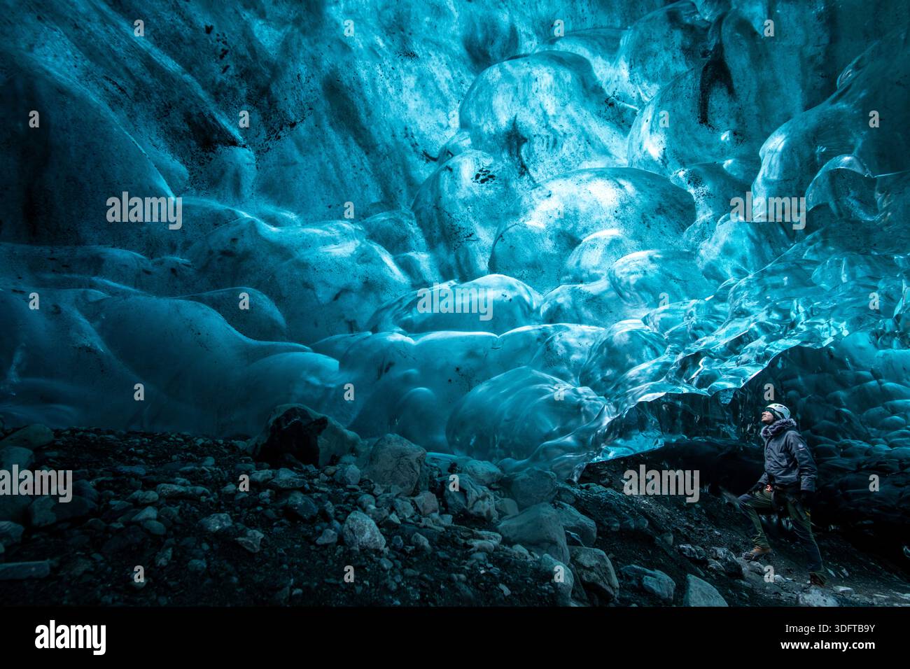 Vue d'un explorateur éclipsé par les formations de glace bleue éthérée dans la grotte de glace Sapphire, une cathédrale gelée de la nature, glacier Vatnajokull, Islande. Banque D'Images