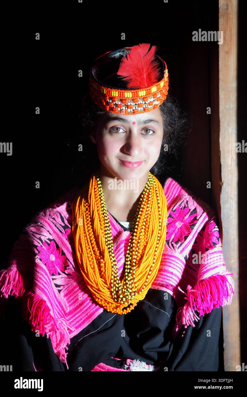 Kalash, Pakistan - 24 décembre 2025 : vue d'une fille Kalash, son sourire radieux contrastant avec le fond sombre, orné d'une tenue traditionnelle avec v Banque D'Images