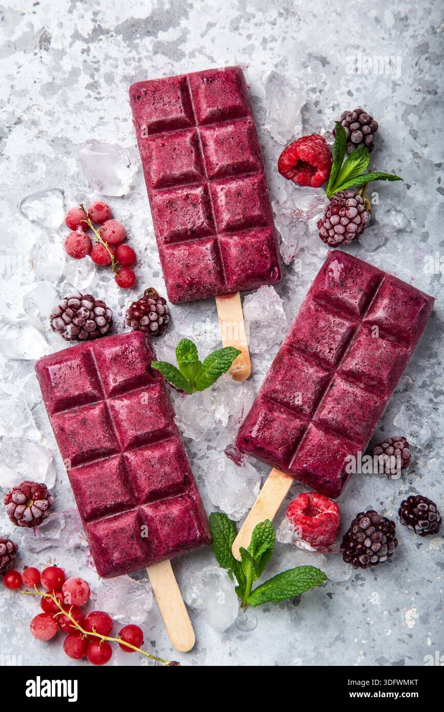baies crème glacée popsicles avec des baies congelées sur fond gris, vue de dessus Banque D'Images