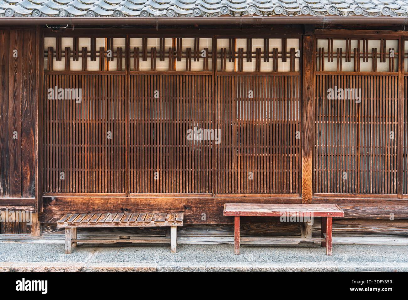 Extérieur rustique de la maison de façade japonaise Machiya avec porte coulissante en bois brun, design en treillis et bancs Banque D'Images