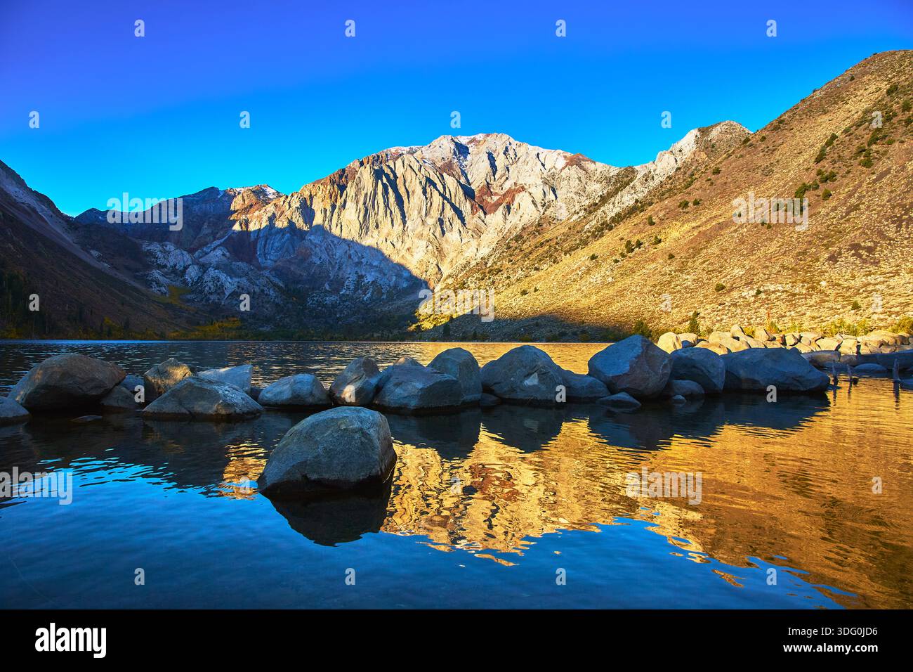 Mountain Lake Sunrise Reflection avec Rocky Shore et Peaks Banque D'Images