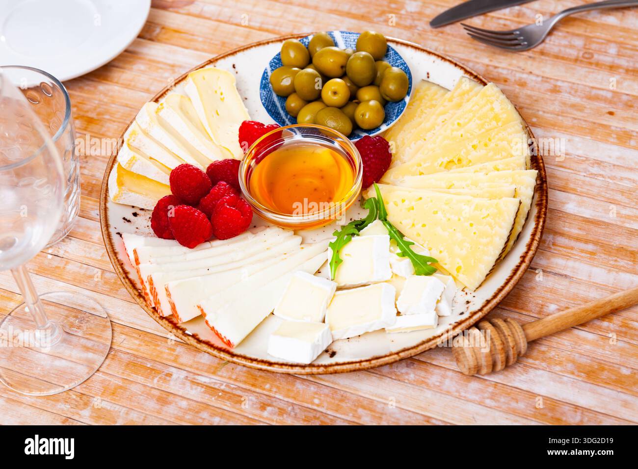 Différents types de fromage, miel, framboises et olives sur bois Banque D'Images