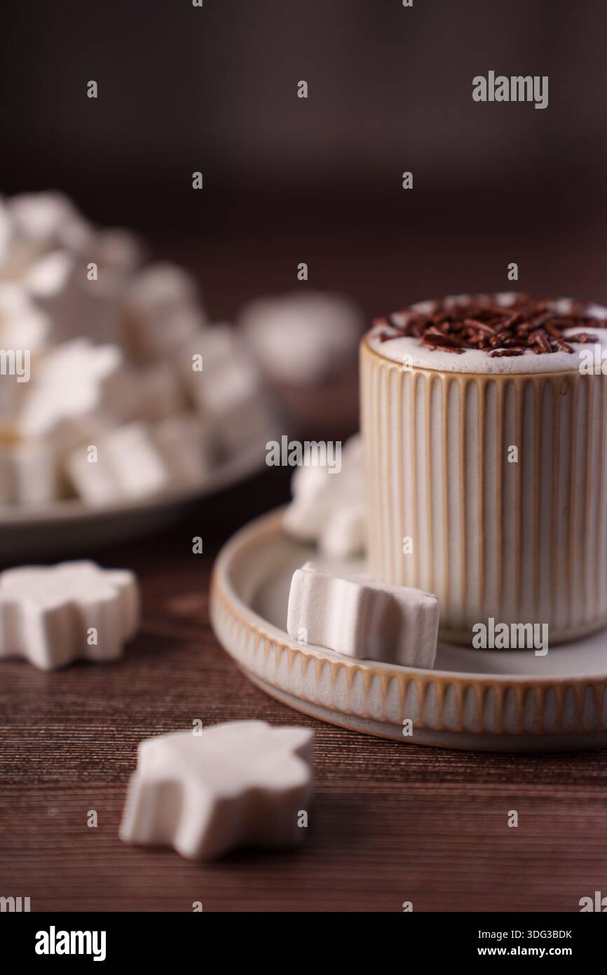 mug en céramique débordant de chocolat chaud crémeux surmonté de copeaux de chocolat et entouré de guimauves en forme d'étoile sur une table en bois rustique, coa Banque D'Images