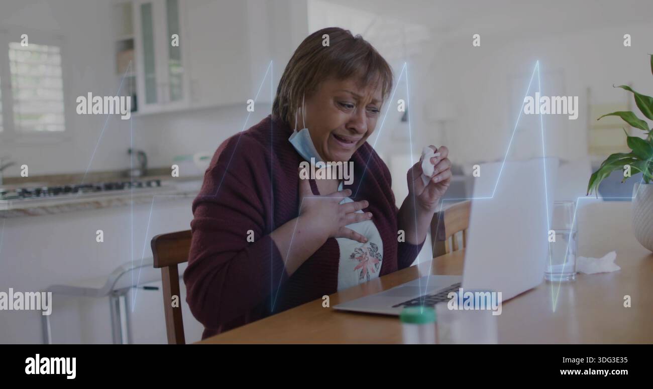 Coiffant la poitrine femme dans le cardigan, cuisine face à l'ordinateur portable tenant le tissu abaissé masque, pilules et ECG Banque D'Images